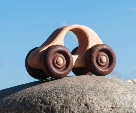 Wooden toy car on a rock with a clear blue sky background