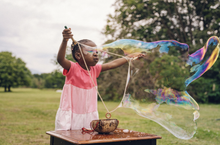 Load image into Gallery viewer, Child blowing a giant bubble with the coconut bucket kit
