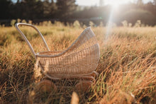 Load image into Gallery viewer, Poppie Rattan Doll Pram in a sunny grassy field
