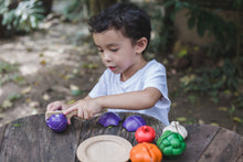 Load image into Gallery viewer, A child playing with a wooden vegetables on a wood table outdoors. The child scuttling the onion

