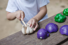 Load image into Gallery viewer, A child cutting a wooden garlic bulb on a wooden table

