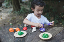 Load image into Gallery viewer, A child playing with a wooden vegetable set on a wood table outdoors. the child has set the two halves of the broccoli on two wooden plates
