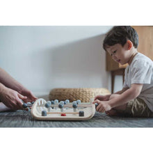 Load image into Gallery viewer, kid playing with a wood soccer game by Plan Toys
