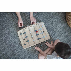 kid playing with a wood soccer game by Plan Toys