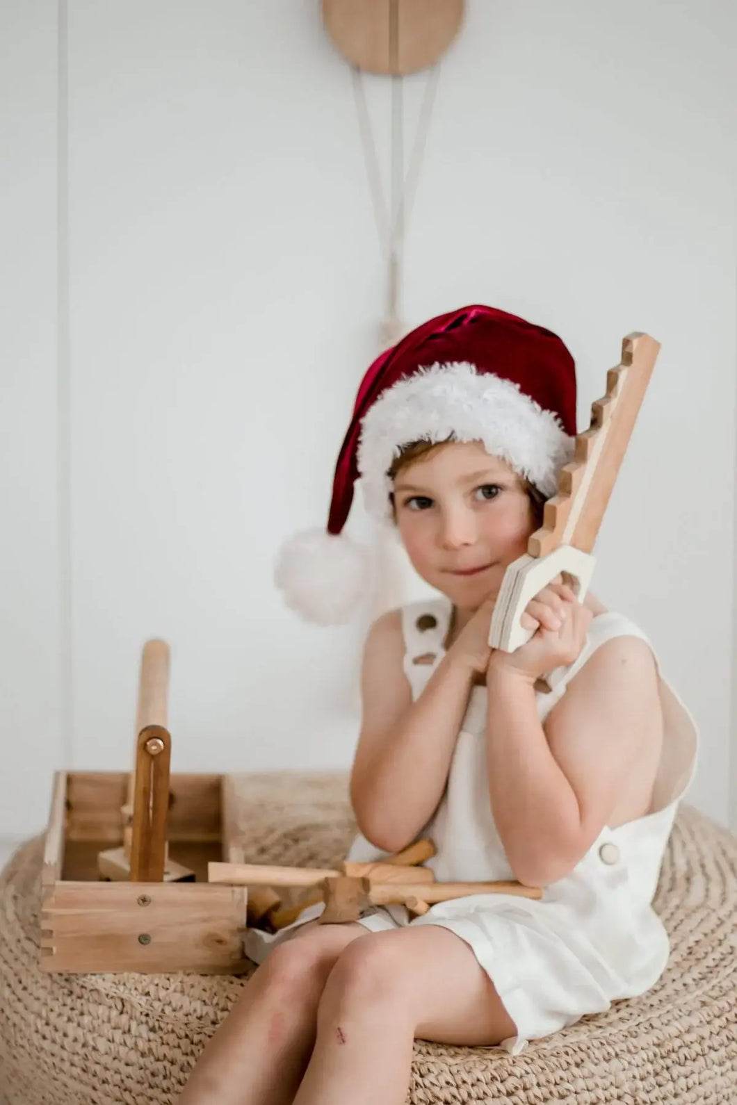 child wearing a Santa hat playing with wooden tool set