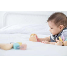 Load image into Gallery viewer, Baby rolling a pastel roller with sound on a bed
