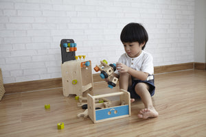 Child Playing with Construction Set and work bench by Plan Toys