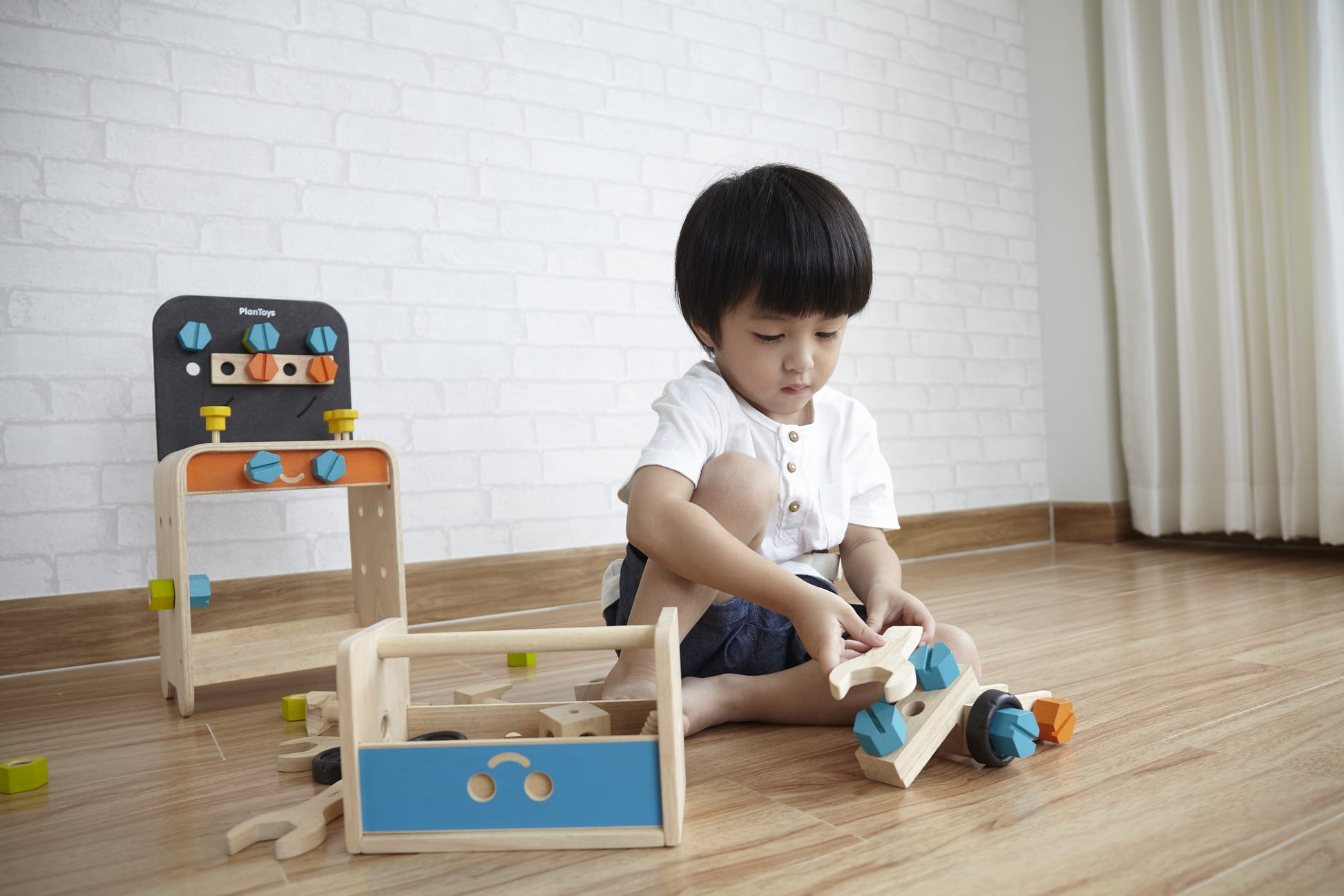 Child Playing with Construction Set and work bench by Plan Toys