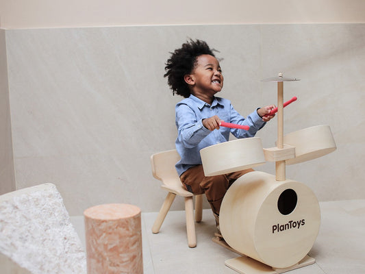 Child playing with Plan Toys Drum Set