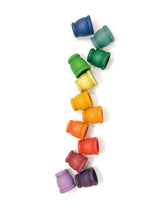Load image into Gallery viewer, Rainbow wooden cups scattered vertically on a plain surface.
