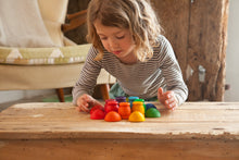 Load image into Gallery viewer, A child playing with rainbow wooden cups and bowls on a wooden table.

