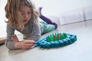 Child playing with coins, green cones, and flames mandalas