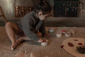 Child sorting the flower petal mandala in wooden cups