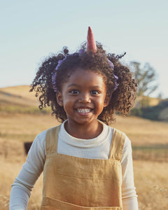 Child wearing unicorn silk headband in a field