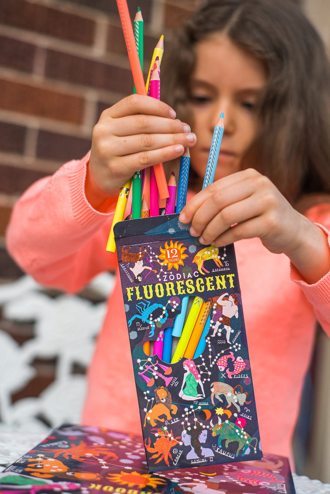 a child putting Zodiac Fluorescent pencils in  a box
