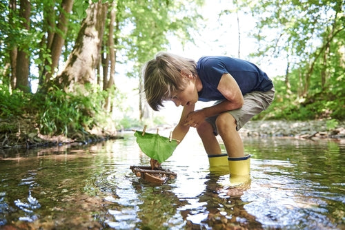 Child playing with Terra Cork Boat in a stream