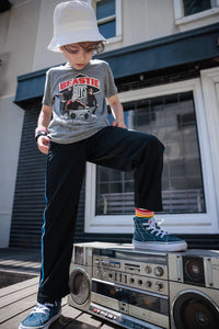 Child standing on a boombox wearing a bucket hat and a grey Beastie Boys short sleeve tee