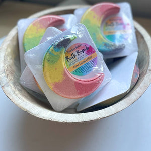 A bowl of moon shaped Tie Dye Rainbow goat milk Bath Bombs with sweet citrus scent