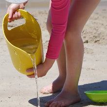 Load image into Gallery viewer, child pouring water out of bamboo sand bucket onto the sand

