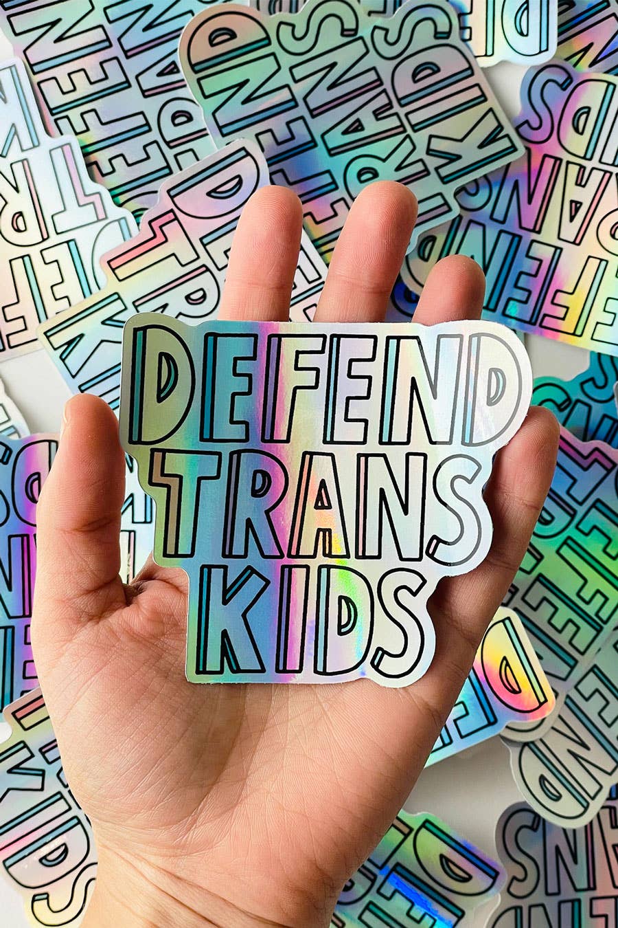 a hand holding a holographic vinyl sticker with the words 
