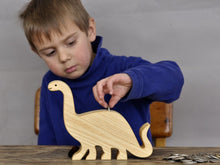 Load image into Gallery viewer, Child inserting coins in a wooden brontosaurus coin bank
