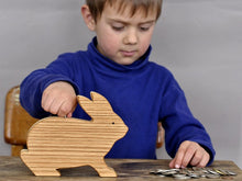 Load image into Gallery viewer, Child inserting coins in a wooden rabbit coin bank
