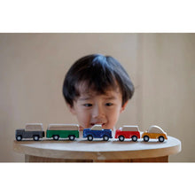 Load image into Gallery viewer, kid looking at plan toy vehicles 
