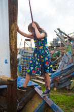 Load image into Gallery viewer, Kid climbing on wooden scraps wearing Organic Forest at Night Kids Skater Dress
