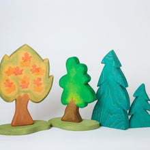 Load image into Gallery viewer, hand made and hand painted wooden trees standing side by side on a neutral back ground. The trees are a maple, and oak, a small and Large Spruce  By Ostheimer
