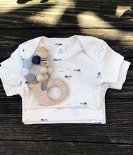 Load image into Gallery viewer,  a stack of Whale Short Sleeve Bodysuits with a whale teether on top 

