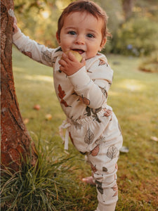 Baby leaning on a tree wearing long sleeve autumn leaf set