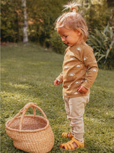 Load image into Gallery viewer, child standing outside by a straw basket wearing organic golden sun long sleeve tee
